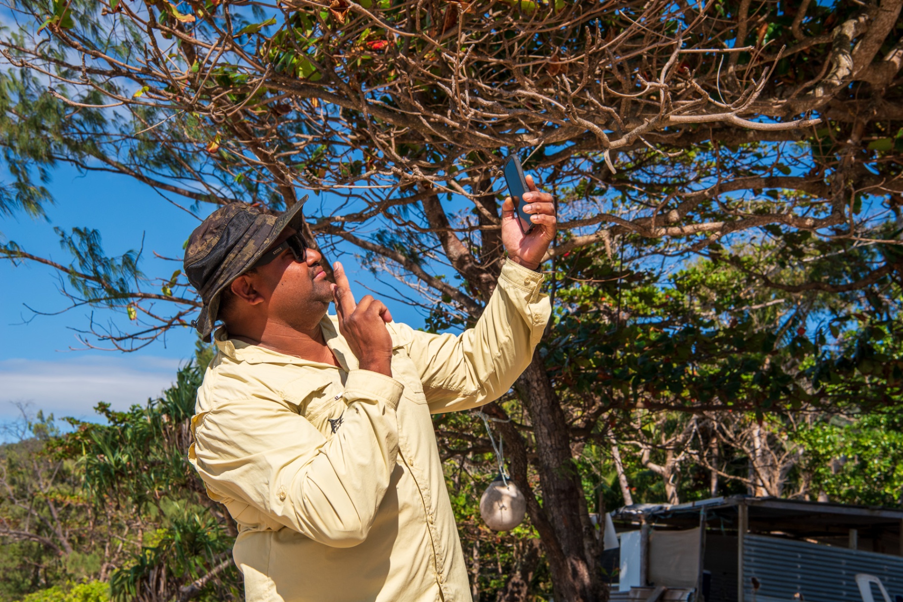 A brother capturing a photo through the trees on Country