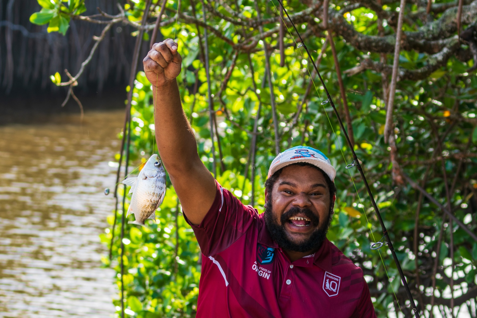 Deadly catch — brother holding up a fish by the mangroves